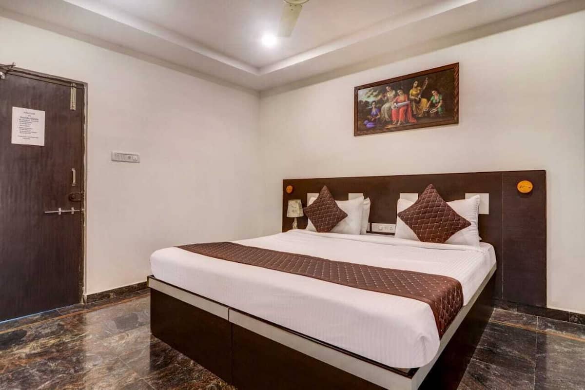 Habitación de hotel con cama, puerta, un cuadro colgado en la pared y suelo de mármol.