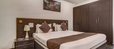 A neatly arranged bedroom with a large bed, a nightstand with drawers, a lamp, and a wardrobe.