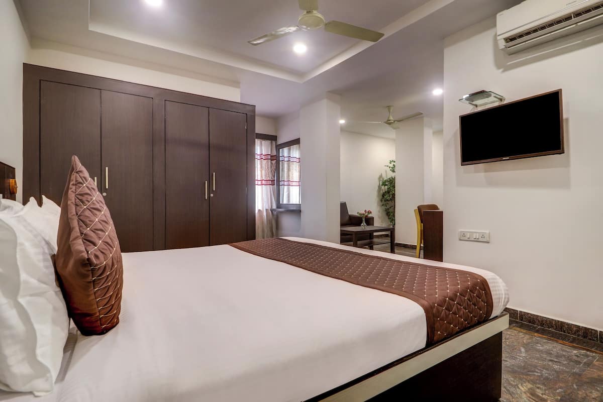 Una habitación de hotel con una cama, un televisor en la pared y un ventilador de techo.