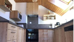 A kitchen with wooden cabinets, a black oven, and a skylight. - Châtel - Roitet : 3P apartment, quiet, breathtaking view in Chalet Lou P'nots  (Châtel)