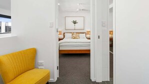 Een hotelkamer met een bed, nachtkastje, plafondventilator, een ingelijst schilderij aan de muur en een raam.