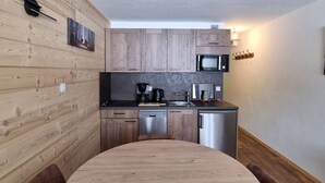 A compact kitchen with wooden cabinetry, a microwave, a coffee maker, and a dishwasher.