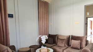 Una sala de estar con un sofá marrón, una mesita redonda y una araña.