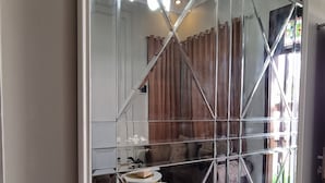 Una habitación con un amplio armario espejado, un sofá, una mesa de centro redonda y un sillón marrón.