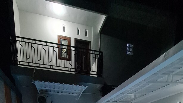 Una piscina interior con un diseño de mosaicos en damero, rodeada de paredes con ventanas y puertas, y un balcón con barandillas.