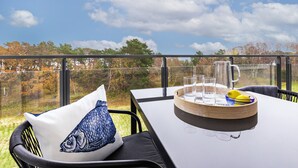 A dining table with a tray, glasses, and a lemon on a balcony with a view of trees and sky. - Sea view for 4 people, 2 en-suite bathrooms, balcony, directly on the beach (Prora (Binz))