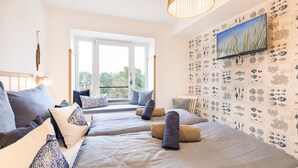 A room with two beds, a large window, and a wall decorated with marine life illustrations. - Sea view for 4 people, 2 en-suite bathrooms, balcony, directly on the beach (Prora (Binz))