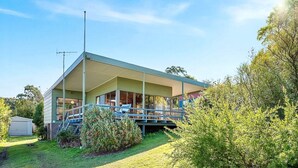 Een huis met twee verdiepingen, een overdekte veranda, een schotelantenne en een kleine schuur in de tuin.