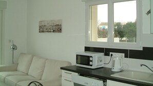 Una cocina moderna con microondas, hervidor y una ventana sobre el fregadero.