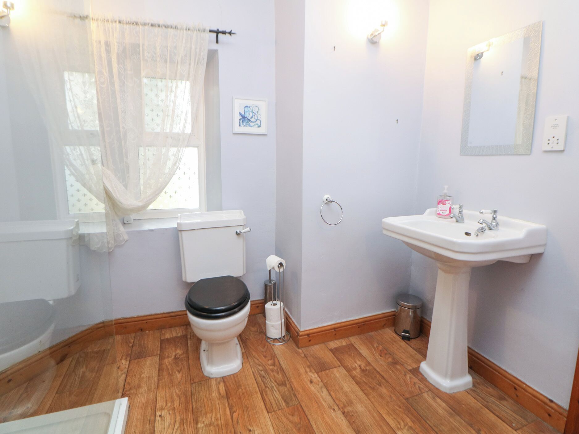Un baño con inodoro, lavabo y suelo de madera.