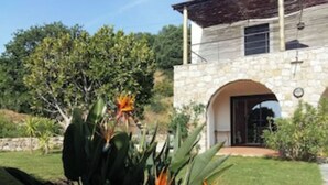 A stone house with a stone archway entrance, surrounded by greenery and a well-maintained lawn. - Villa Cursaninco - sea view (Corbara)