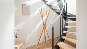 A modern staircase with wooden steps and a black railing, leading to an upper floor. - House Salz&Sand // Apartment Lüttje Tide (Norderney)