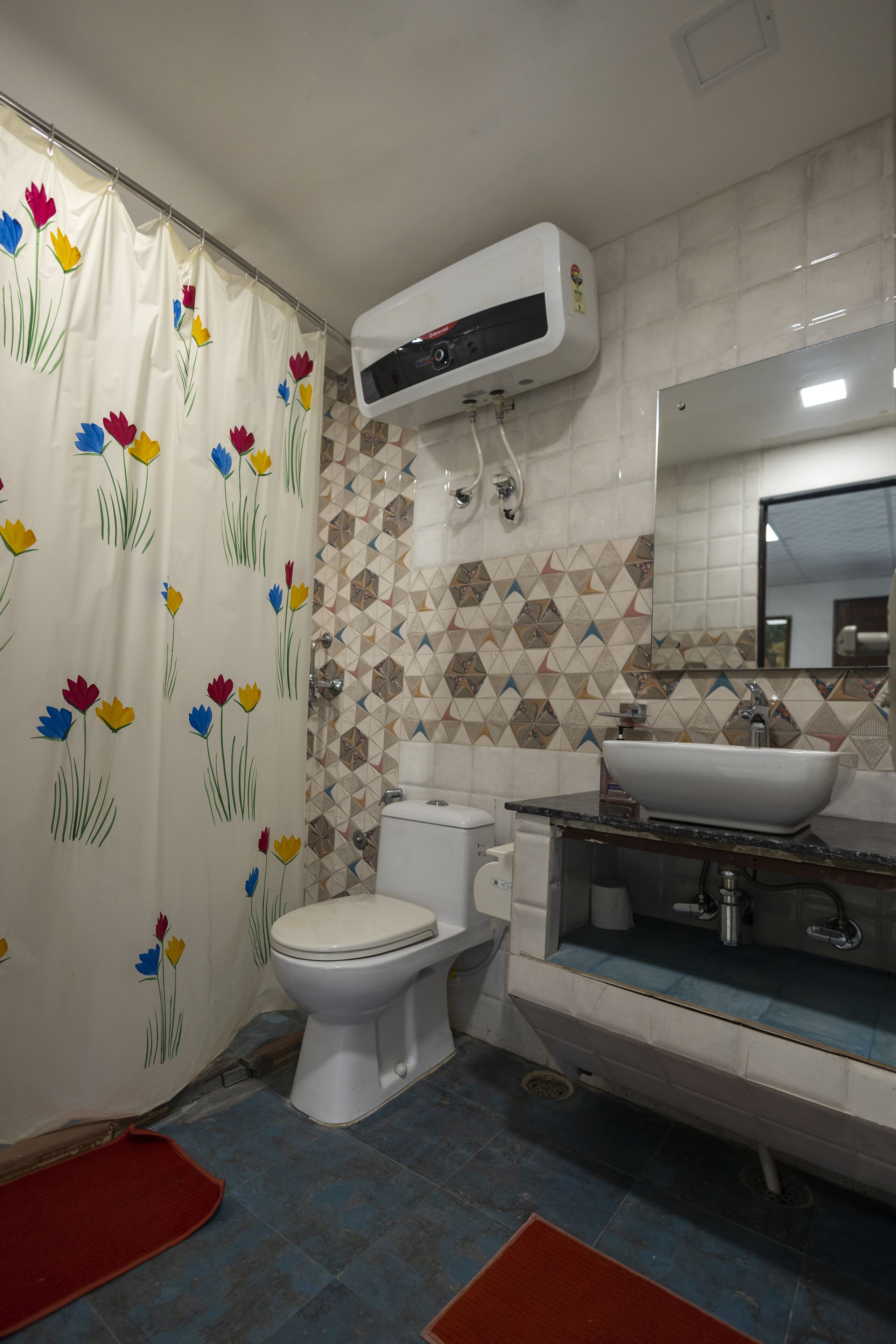 A bathroom with a toilet, sink, and shower curtain with floral patterns.