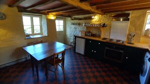 A kitchen with a checkered floor, a wooden table, and a washing machine. - Luxurious Cottage with Lovely Views in Rural Location (Norton Presteigne)