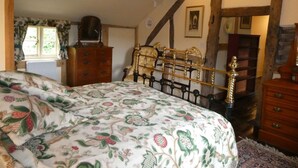 A bedroom with a bed, wooden beams, a dresser, and a window with curtains. - Luxurious Cottage with Lovely Views in Rural Location (Norton Presteigne)