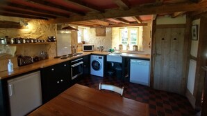 A compact kitchen with a wooden table, a washing machine, and a microwave. - Luxurious Cottage with Lovely Views in Rural Location (Norton Presteigne)