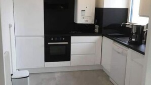 A compact kitchen with white cabinets, a black countertop, and a built-in oven.