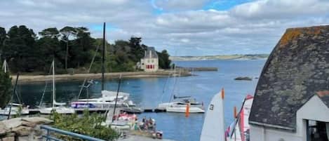 A coastal view with boats, a white building, and a blue railing.