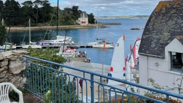 A coastal view with boats, a white building, and a blue railing.