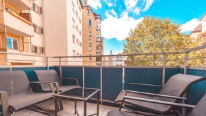 A balcony with outdoor seating and a view of a tree and buildings. - Central, modern designer appartment in downtown Stuttgart (Stuttgart)