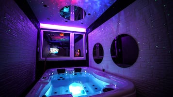 Relax in a serene spa room with a central hot tub, wall-mounted mirrors, and a window offering a view of the outside.