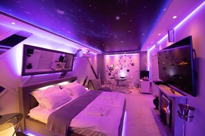 A modern hotel room with a bed, a desk, a TV, and a fireplace. - Aurora Lux Spa (Belgrade)