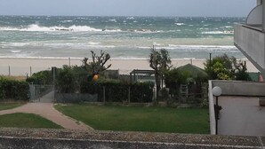 Vista del océano desde una zona residencial, con un camino que lleva a una entrada con portón.