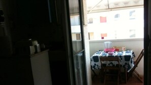 Un pequeño comedor con una mesa cubierta con mantel floral, sillas y un refrigerador al fondo.