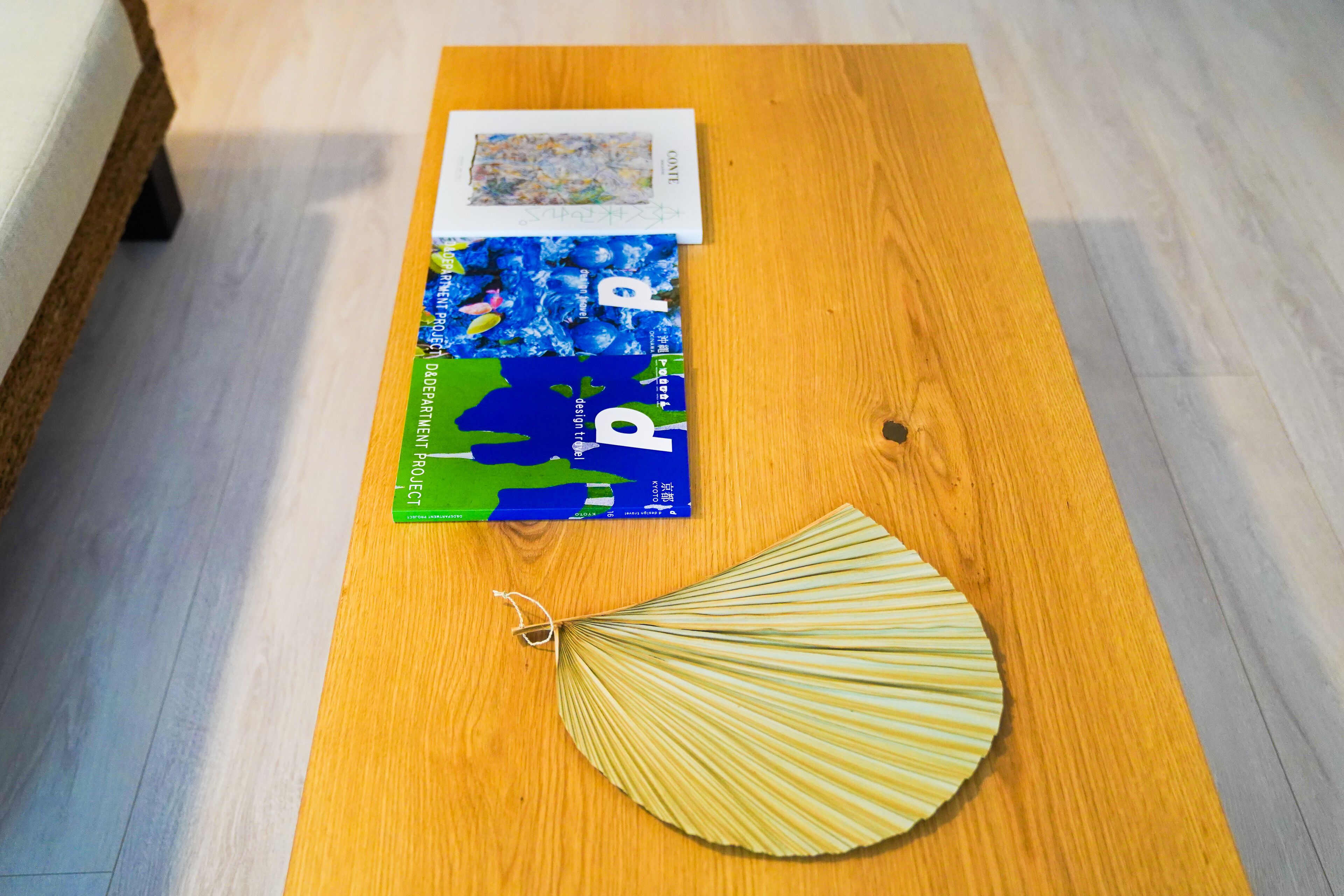 Ein Holztisch mit einem Buch und einem Ventilator darauf.