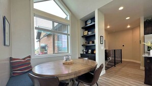 A modern kitchen with a round wooden table, two chairs, a window with blinds, and built-in shelves with various items. - Luxurious Family Home in Driggs - Hot Tub (Driggs)