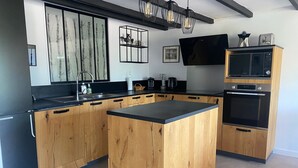 Una cocina moderna con armarios de madera, encimera negra, horno empotrado, microondas y una isla grande.