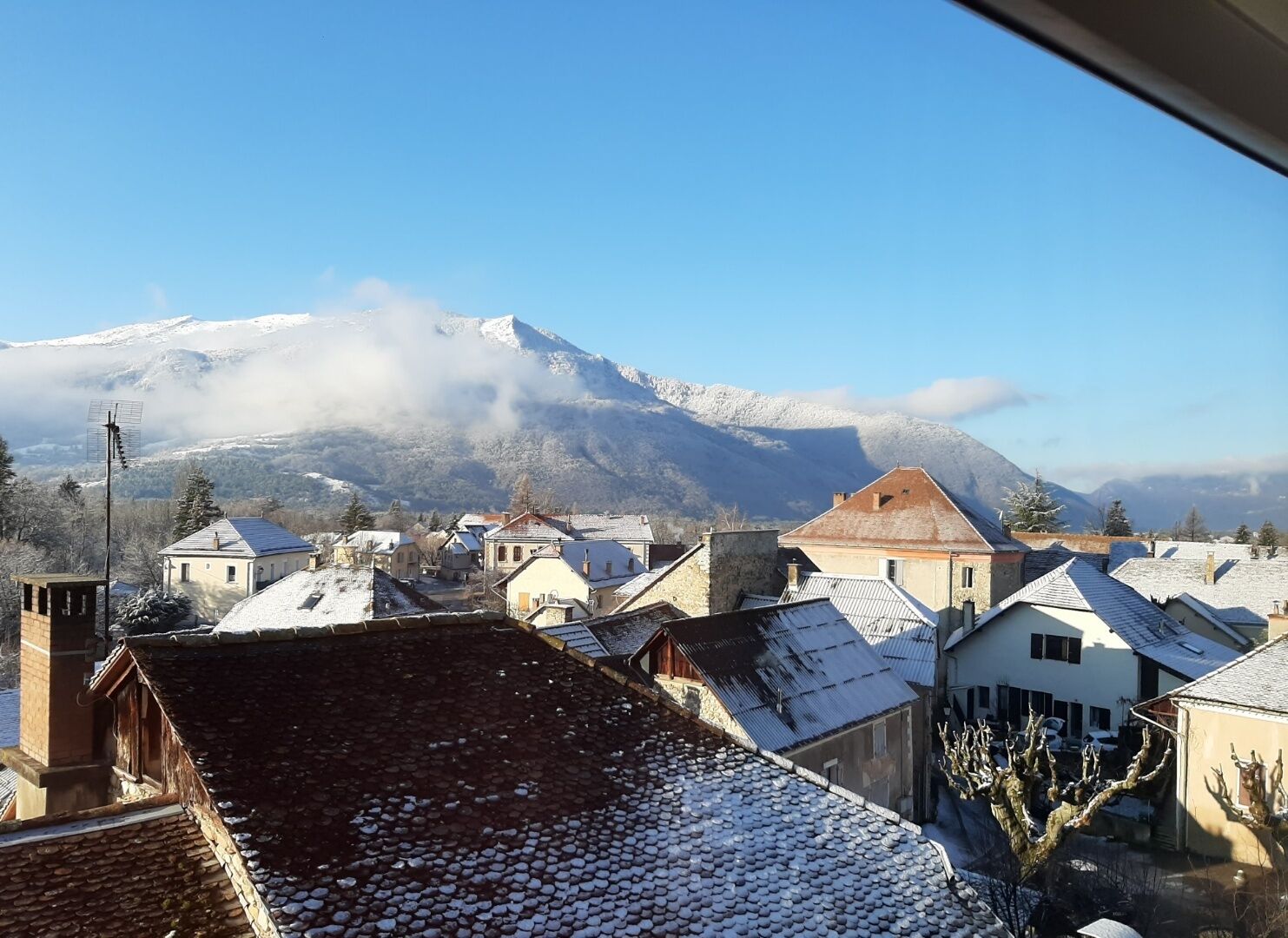 A town with snow-covered rooftops and a mountain in the background.
