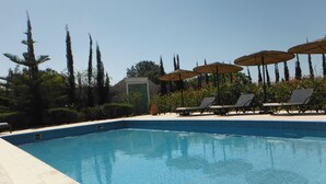 A swimming pool with lounge chairs and umbrellas, surrounded by greenery and a building in the background. - Modern villa with swimming pool just è kms from Essaouira (Essaouira)