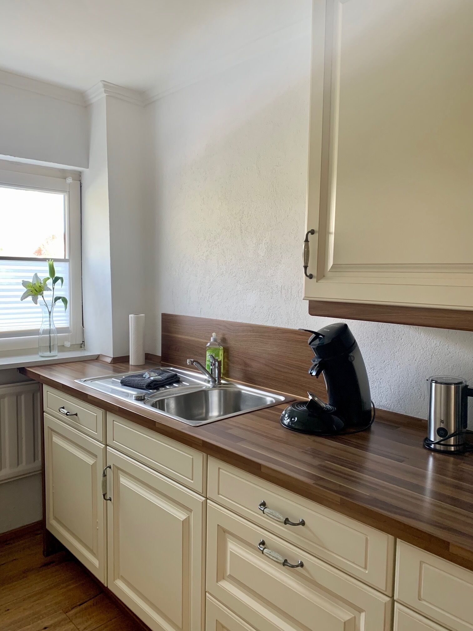 Una cocina con encimera de madera, pileta de acero inoxidable y cafetera.