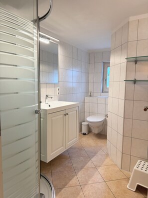 Une salle de bain moderne avec une douche à parois de verre, un lavabo blanc et des toilettes.