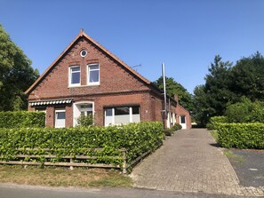 Une maison en briques rouges, avec un toit triangulaire, une porte d’entrée et un petit porche.