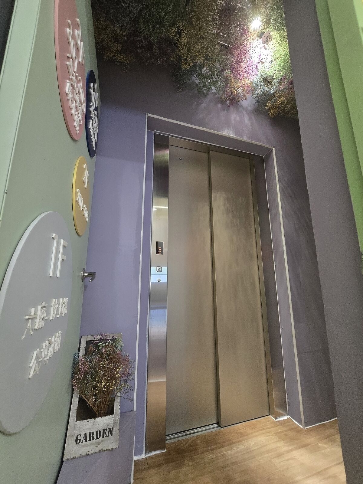 A room with a sliding door, a wall-mounted clock, and a small window with a plant labeled 'GARDEN'.