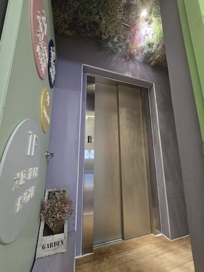 Una habitación con puerta corredera, un reloj fijado a la pared y un pequeño ventanal con una planta que dice 'JARDÍN'.