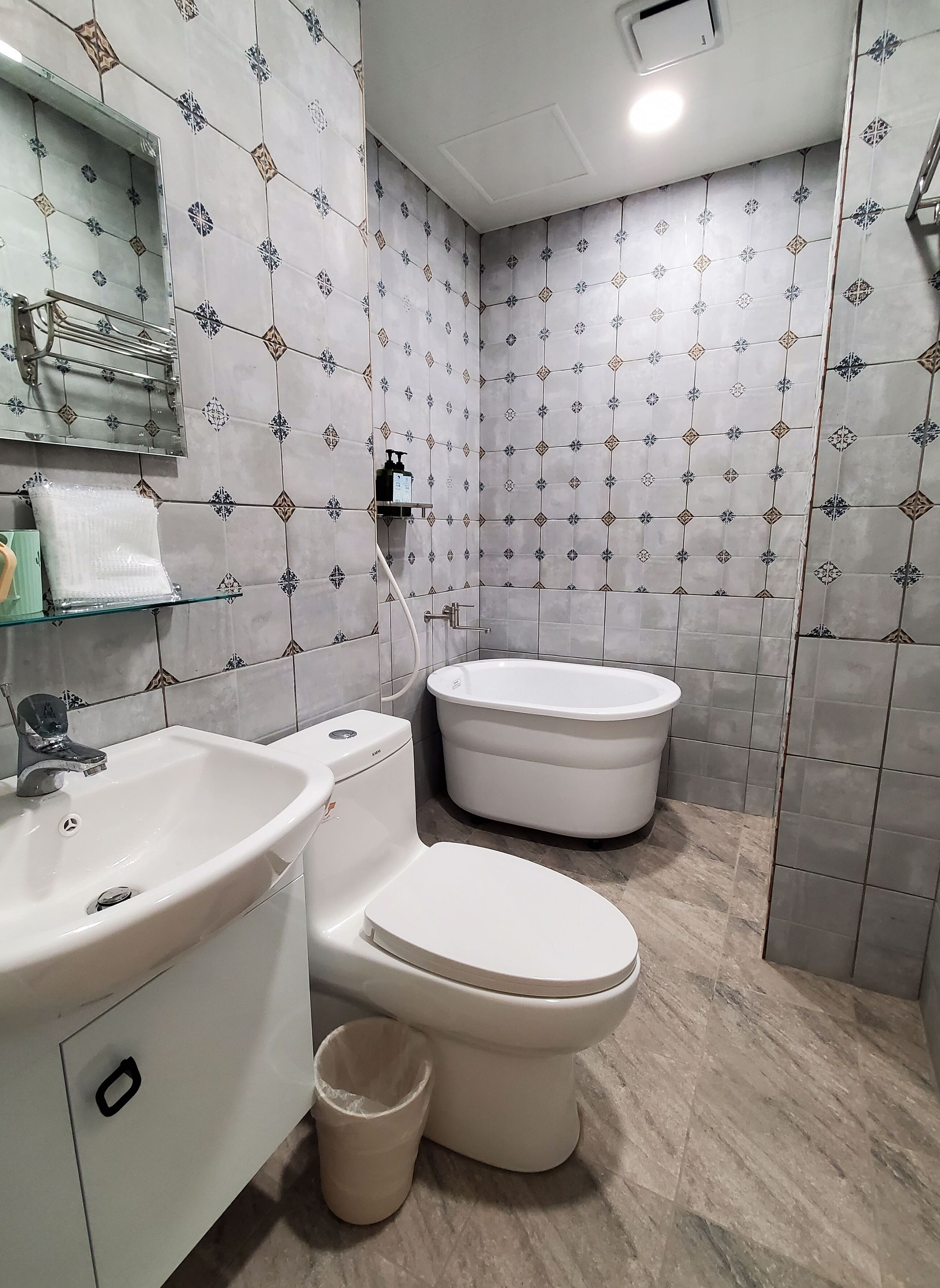 A bathroom with a sink, toilet, and bathtub, tiled with a geometric pattern.