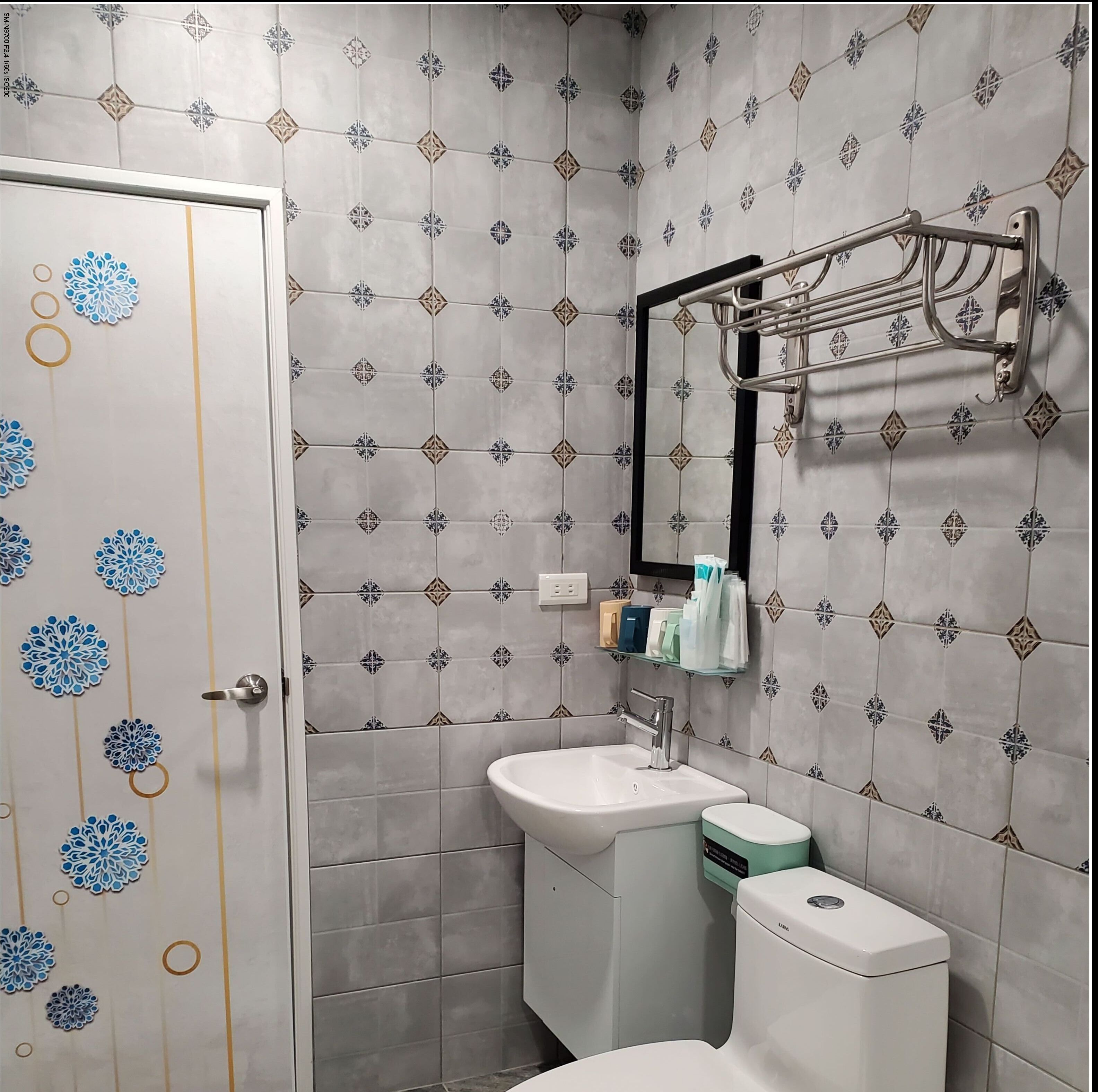 A bathroom with patterned tiles, a sink, a toilet, and a towel rack.