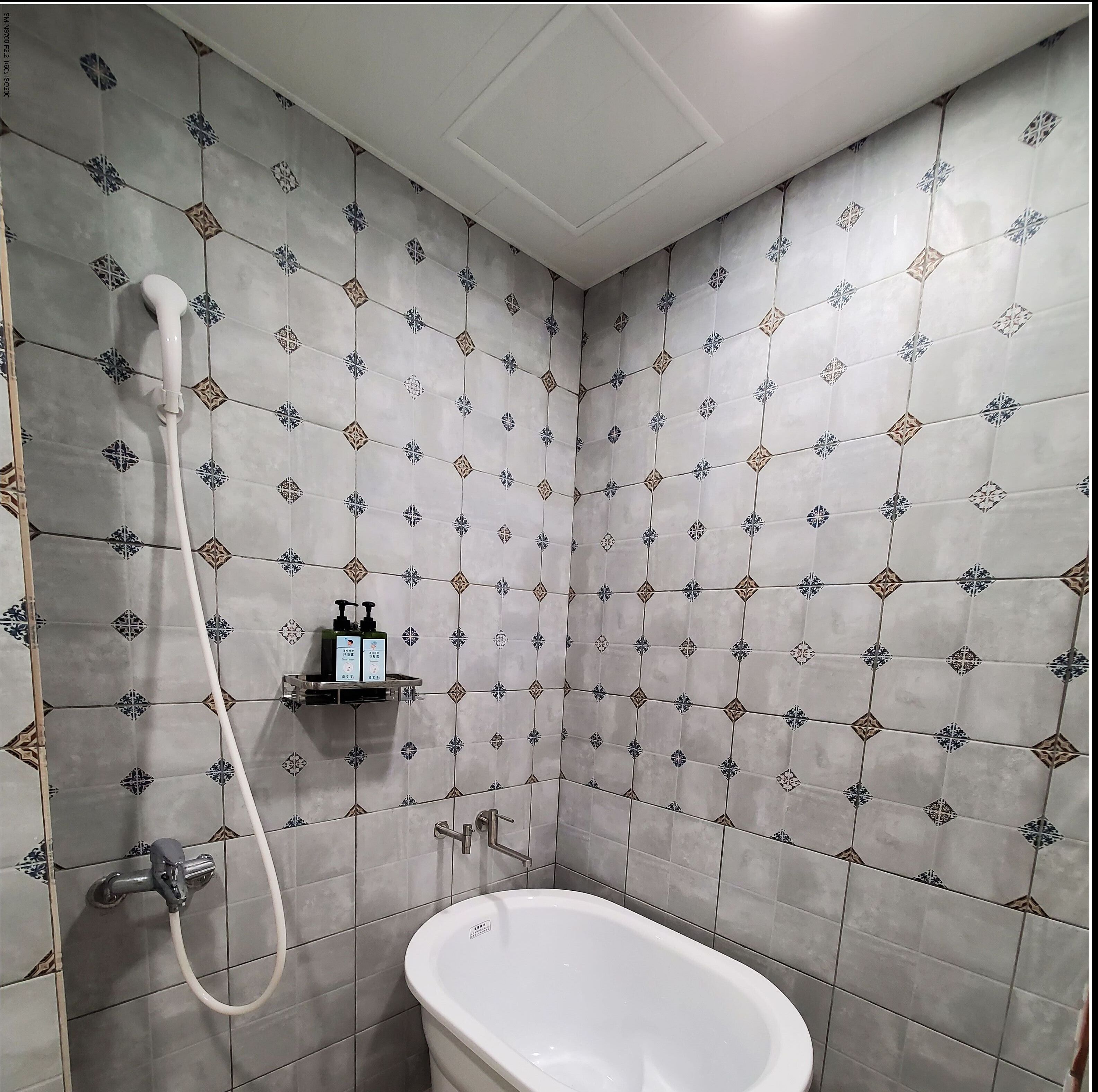 A bathroom with a bathtub, a shower, and a shelf with toiletries.