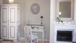 A room with a white desk, a chair, a clock, a chandelier, a fireplace, and a mirror. - Charming house for 6 people in EGUISHEIM - Gîte HIRONDELLE (Eguisheim)
