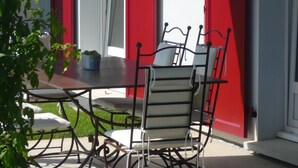 A patio with a table and chairs, red shutters, and a potted plant. - Charming house for 6 people in EGUISHEIM - Gîte HIRONDELLE (Eguisheim)