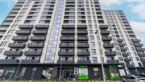 A high-rise building with multiple balconies and a storefront at the ground level.