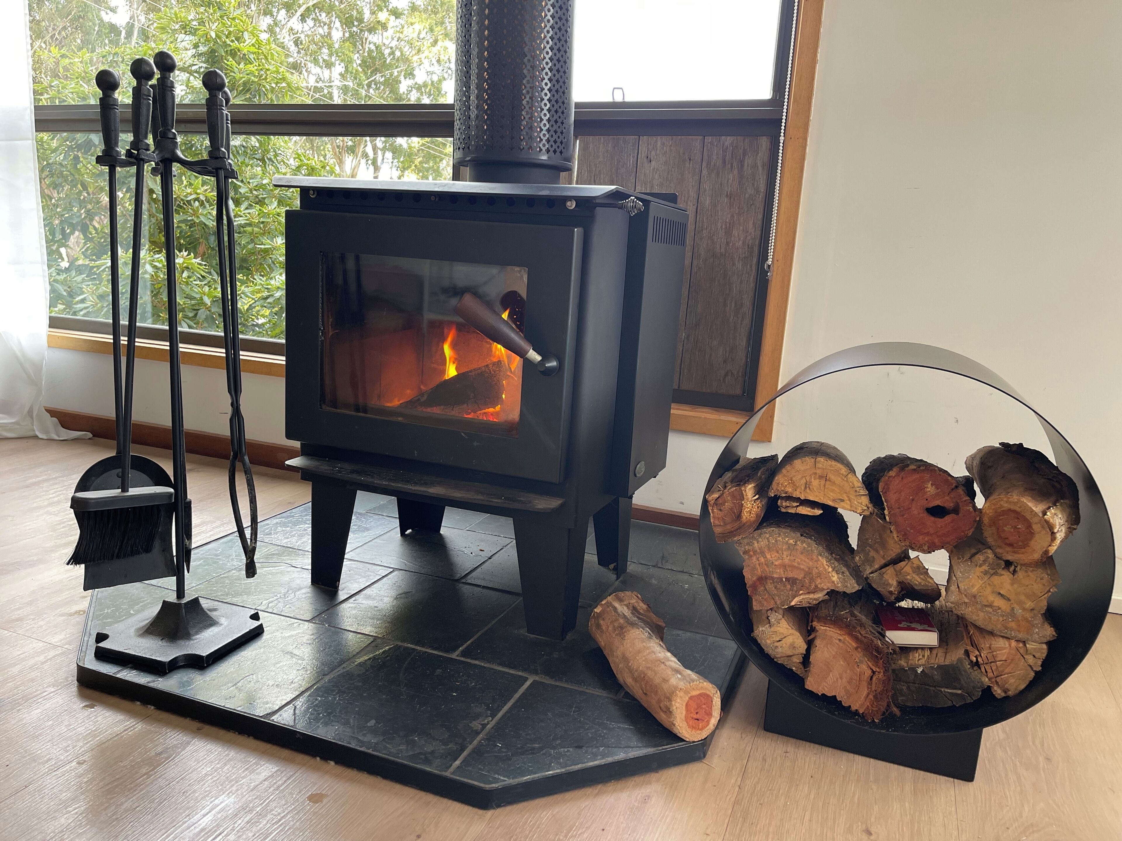 A wood-burning stove with logs and a broom.