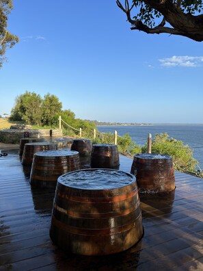 Des barils en bois disposés sur une terrasse en bois, avec vue sur la mer.