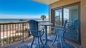 A balcony with a view of the beach, two chairs, and a small table. - Beachfront Beauty: Condo with Pier Access! (Fernandina Beach)