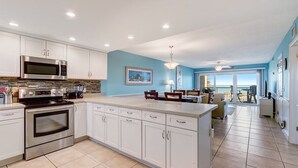 A modern kitchen with white cabinets, stainless steel appliances, and a large island. - Beachfront Beauty: Condo with Pier Access! (Fernandina Beach)