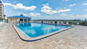 A swimming pool with lounge chairs and a building with a blue roof. - Beachfront Beauty: Condo with Pier Access! (Fernandina Beach)
