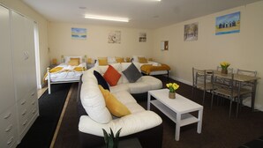 A modern living room with a sofa, a dining table with chairs, and artwork on the walls. - Annex St Ann's (Rotherham)
